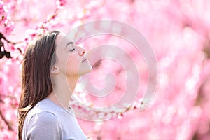 Woman breathing and smelling in a pink flowered field