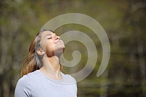 Woman breaths fresh air in a sunny forest or park