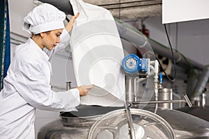 Woman brewer pouring beer yeast into tank