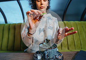 Woman brewing a fresh mug of tea with teabag in cafe