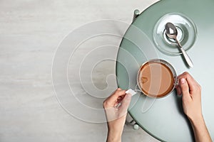 Woman brewing tea with bag in cup at table, top view