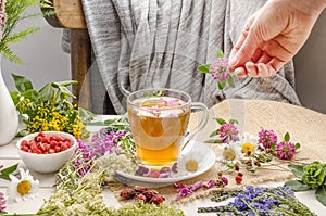 A woman brews herbal tea in a glass cup with clover