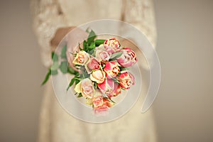 Woman bride hands holding spring flowers tulips and roses, boho wedding dress