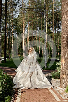 Woman bride in a luxurious puffy wedding dress runs along the path to the wedding