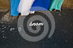 Woman bride maids in colorful blue dresses stand by a sign. Dream