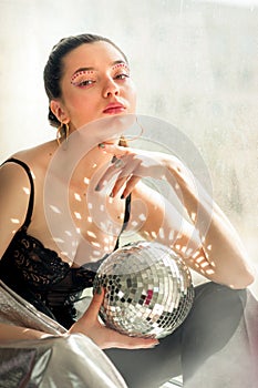 woman with bright colorfull spice makeup and Mirror disco ball with shines on shes body