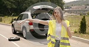 Woman with broken car asking for help at highway