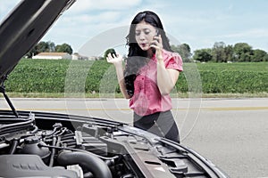 Woman with broken car asking help on the road