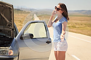 Woman with broken car on the road calling for help