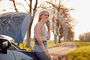 Woman With Broken Down Car On Country Road Calling For Help On Mobile Phone