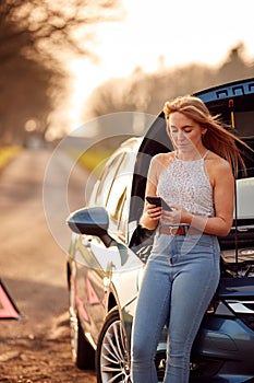 Woman With Broken Down Car On Country Road Calling For Help On Mobile Phone