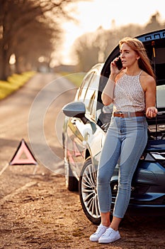 Woman With Broken Down Car On Country Road Calling For Help On Mobile Phone