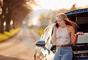Woman With Broken Down Car On Country Road Calling For Help On Mobile Phone