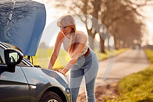Woman Broken Down On Country Road Looking Under Bonnet Of Car 