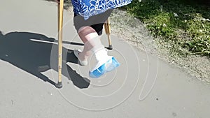 A woman with a broken leg in a white medical plaster jumps on crutches. A difficult life situation for an adult. Limited mobility