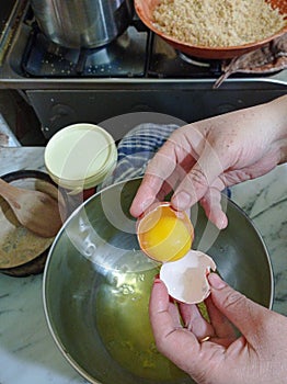 Woman broking egg to prepare cake