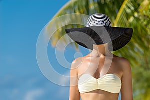 Woman with bronze tan enjoying beach relaxing joyful in summer by tropical blue water.