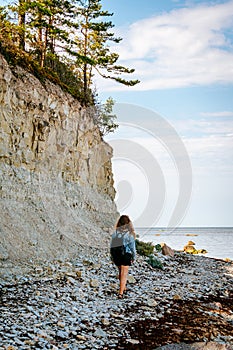 Woman with brown curly hair hiking by the Panga cliff in Saaremaa, Estonia during sunny day. The highest bedrock outcrop in