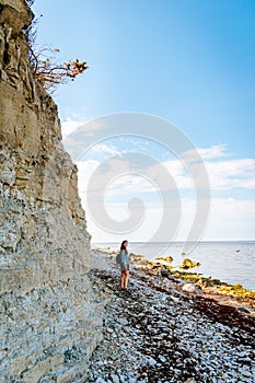 Woman with brown curly hair hiking by the Panga cliff in Saaremaa, Estonia during sunny day. The highest bedrock outcrop in