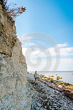 Woman with brown curly hair hiking by the Panga cliff in Saaremaa, Estonia during sunny day. The highest bedrock outcrop in