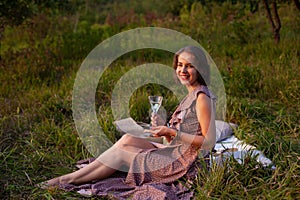 A woman in brown dress sits on a picnic in a park with panoramic view