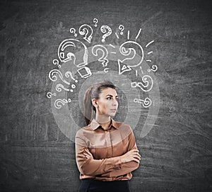 Woman in brown and question marks on chalkboard