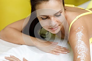 Woman brunette getting salt scrub treatment in spa salon