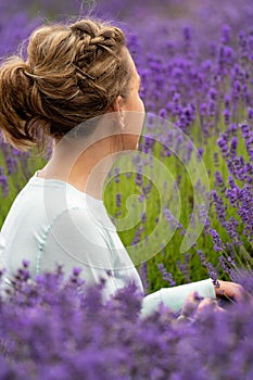 Woman with brunette hair sits and looks away, while posing in a field of lavender flowers in Sequim Washington