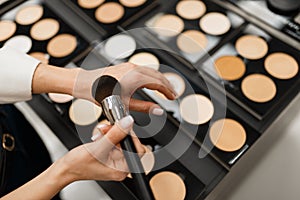 Woman with brush choosing shadows tone in store