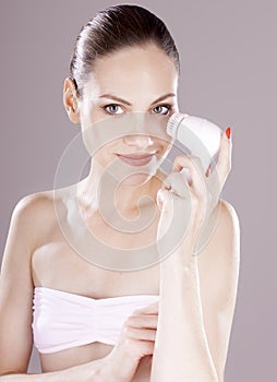 Woman with brush for deep cleansing facial.