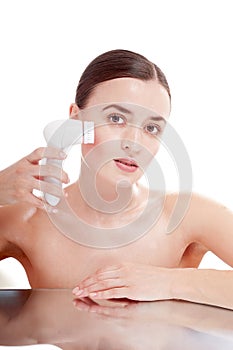 Woman with brush for deep cleansing facial.