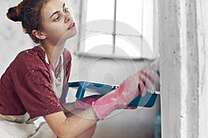 woman with brush in hands paint inside home interior renovation