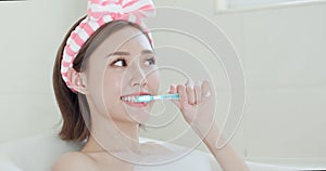 Woman brush tooth in bathtub