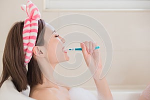 Woman brush tooth in bathtub