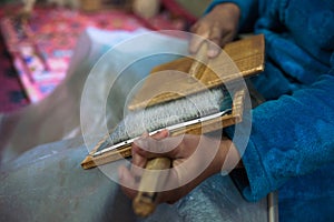 Woman with brushes preparing a wool for spining a woolen string for berber moroccan carpets