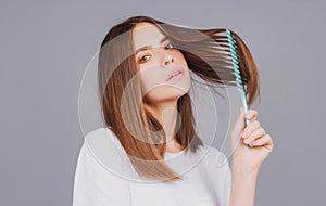 Woman brushing straight natural hair with comb. Girl combing long healthy hair with hairbrush. Hair care beauty concept