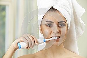 Woman Brushing Teeth With Electric Toothbrush In Bathroom