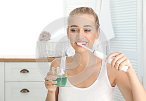 Woman brushing teeth and holding glass