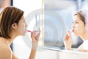 Woman brushing teeth and looking in the mirror