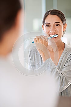 Woman, brushing teeth and smile in home by mirror for health, wellness or self care for breath in morning. Girl, person