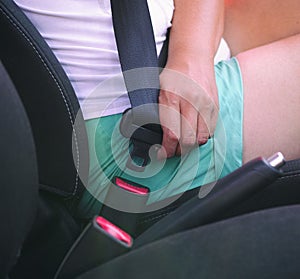 Woman buckles up the seat belt before driving car