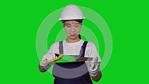 Woman builder in blue overalls and white hard hat helmet with hand saw.
