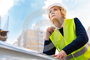 A woman Builder at a construction site inspects a house made of brick