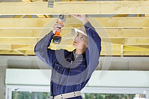 Woman builder drilling wood