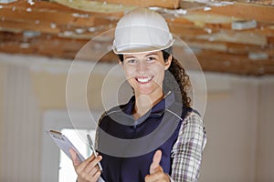 woman builder holding clipboard shows thumb up