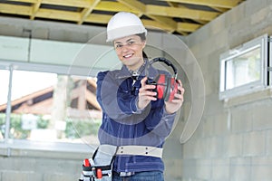 Woman builder holding ear protection