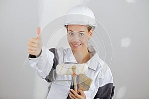 Woman builder holding wrench showing thumb up