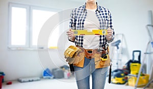 Woman builder with level and working tools on belt