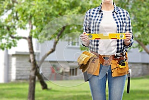 Woman builder with level and working tools on belt