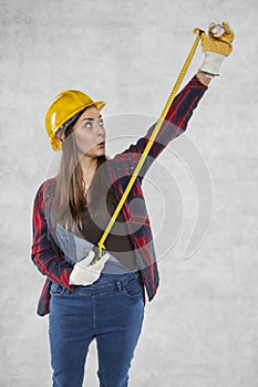 Woman builder stretches a meter, surprised face